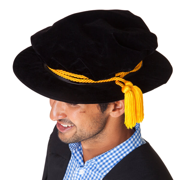 Top view of a black velvet PhD hat with gold cord