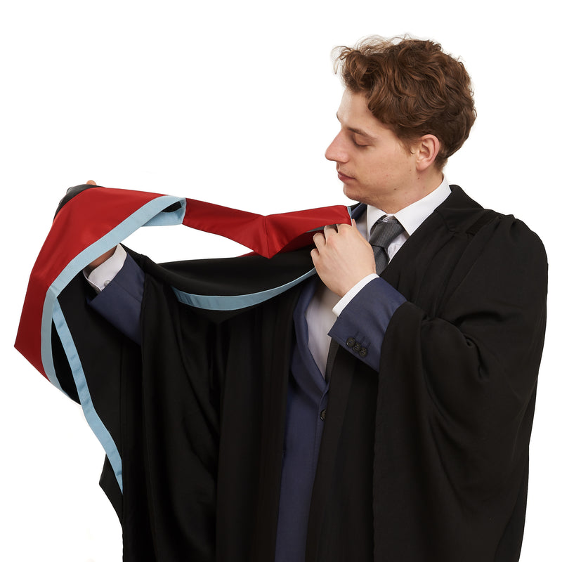 Man holding a graduation hood, wearing a graduation gown